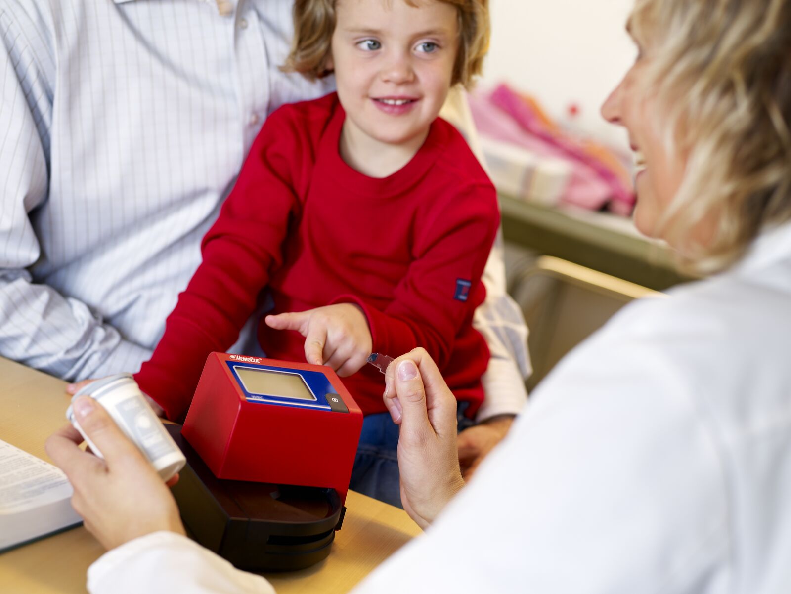 Young girl pointing at a HemoCue WBC Analyzer with a female doctor smiling