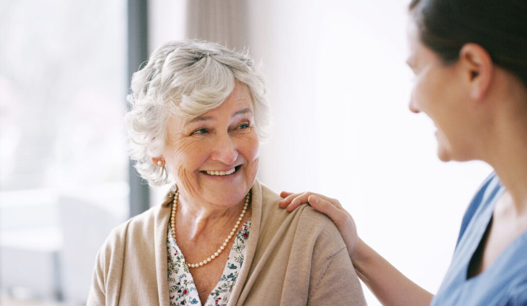 Female nurse smiling at elderly female patient