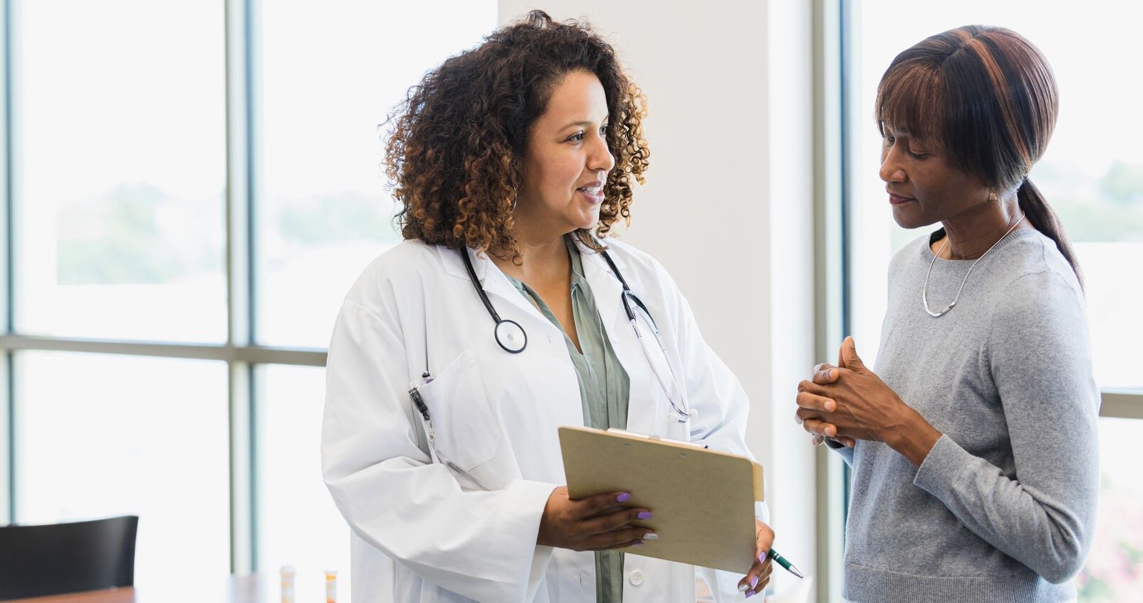 Female doctor having a conversation with a femalte patient looking at a journal