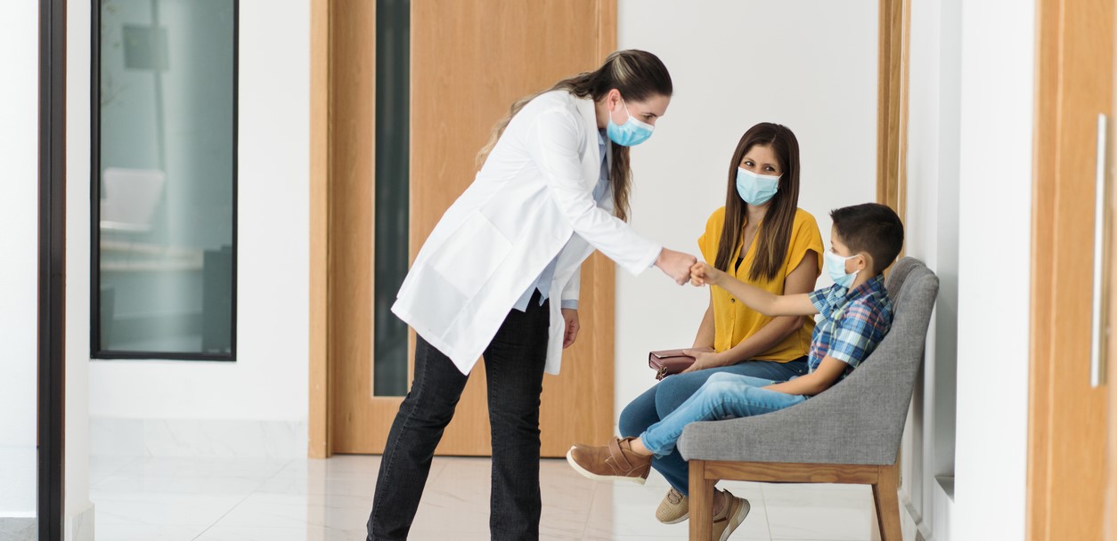 Female doctor with child and mother in primary care clinic