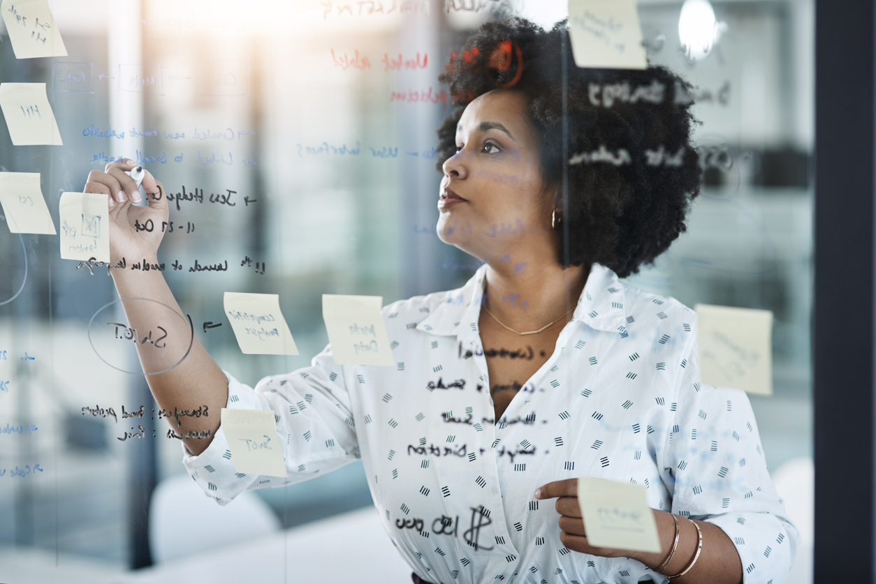 Shot of a young businesswoman brainstorming on a glass wall in an office