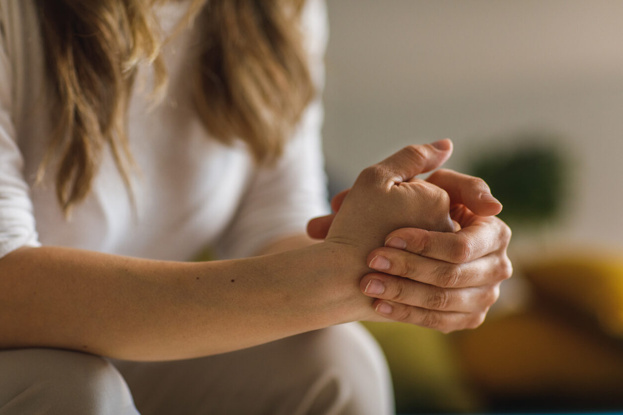 Midsection of unrecognizable White woman struggling with anxiety and cracking her knuckles while contemplating problems.